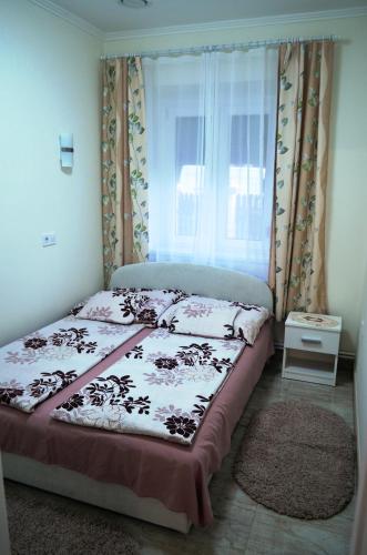 a bed in a room with a window and a bedspread at Henrietta - Violetta Apartman in Hajdúszoboszló