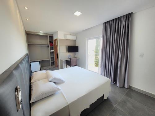 um quarto com uma grande cama branca e uma janela em Hotel Conchas em Penha