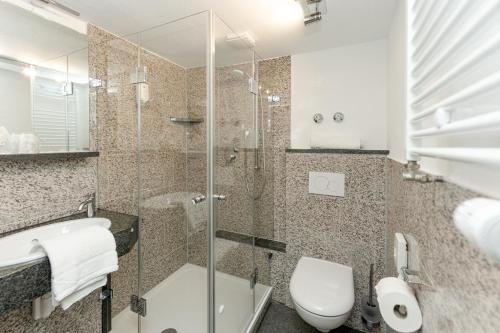 a bathroom with a toilet and a glass shower at Hotel & Restaurant Fischer in Altenstadt