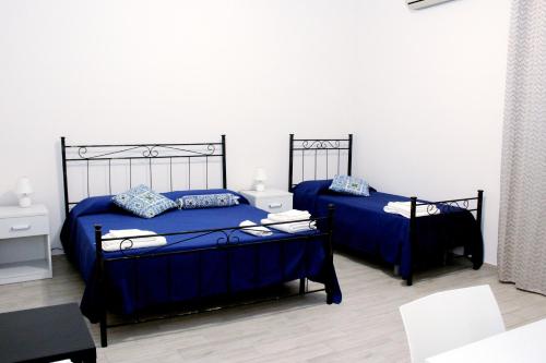 2 Betten mit blauer Bettwäsche in einem weißen Zimmer in der Unterkunft B&B Ciccannina in Rosolini