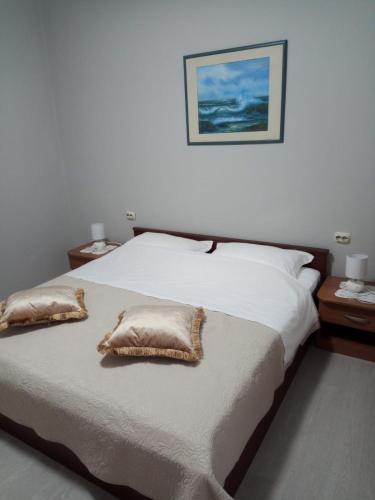 a bedroom with a bed with two pillows on it at Apartmani Ivana in Novalja