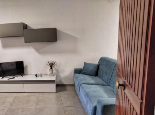 een woonkamer met een blauwe bank en een tv bij Casa Spinuzza 4 in Cefalù