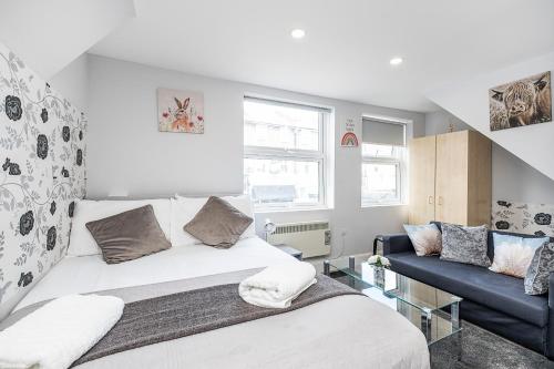 um quarto com uma cama e um sofá azul em Securematics Queens Studio Apartments em Londres