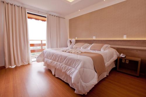 a bedroom with a large bed and a large window at Hotel Bel Air in Teresópolis