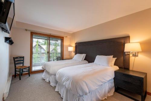 een slaapkamer met 2 bedden en een raam bij Cozy Condo with Slope Side View Ski on Ski Out Access w HOT TUB and Pool in Whistler
