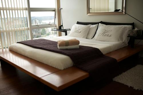 a large bed with a brown blanket and a window at Your Alternative to a Five Star Hotel - Premium Location in Vancouver