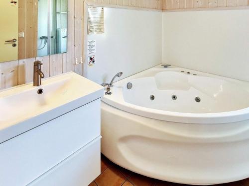 Baño blanco con bañera y lavamanos en Two-Bedroom Holiday home in Grömitz 2, en Grömitz