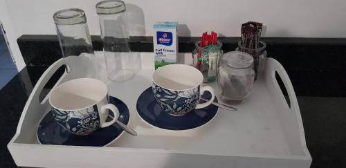 a white cabinet with two cups and plates on it at Forget me not Selfcatering Apartments in Nelspruit