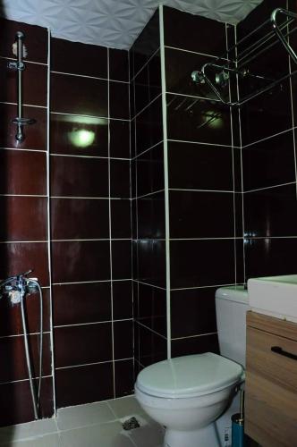 a bathroom with a toilet and a brown tiled wall at Kemer Port Garden in Kemer