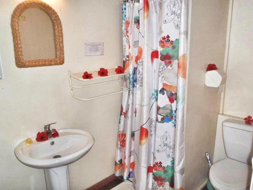 a bathroom with a sink and a shower curtain at HUAHINE - Bungalow Ylang Ylang in Fare