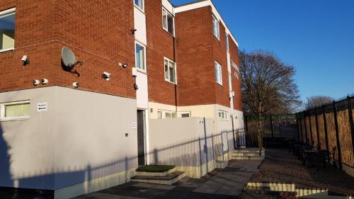 a brick building with a white fence next to it at Summerhill House Apartments in Elswick