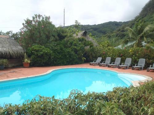 a blue swimming pool with chairs and trees at HUAHINE - Bungalow Vanille 2p in Fare