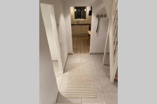 a hallway with a white tile floor and a kitchen at Central kælder lejlighed in Give