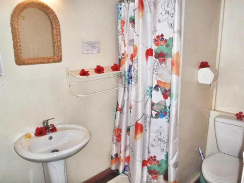baño con lavabo y cortina de ducha en HUAHINE - Bungalow Tiare, en Fare