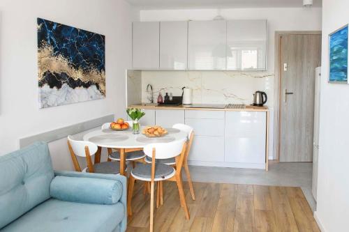 une cuisine et une salle à manger avec une table et un canapé bleu dans l'établissement Przy Brzegu - Hel studio, à Hel