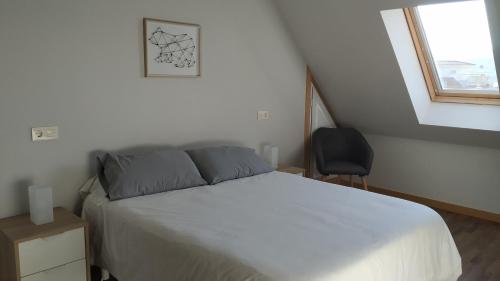 um quarto com uma cama, uma cadeira e uma janela em Apartamentos Descubre Rías Baixas em Catoira