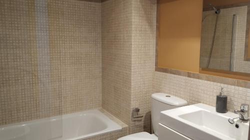 uma casa de banho com uma banheira, um WC e um lavatório. em Apartamentos Descubre Rías Baixas em Catoira