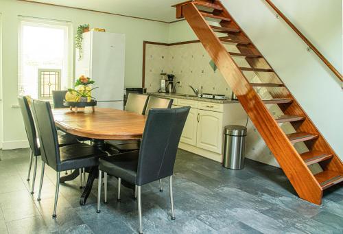 una cocina con mesa de madera y sillas y una escalera en B&B De Horizon, en Urk