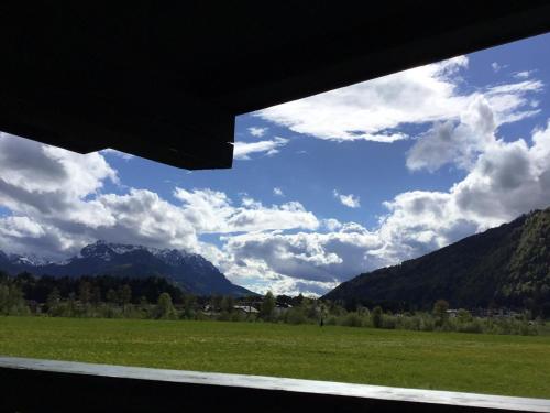 a view from a window of a field and mountains at Ferienwohnung Orchidee in Kössen