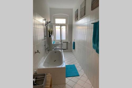 ein weißes Badezimmer mit einer Badewanne und einem Waschbecken in der Unterkunft Holiday apartment in Leipzig