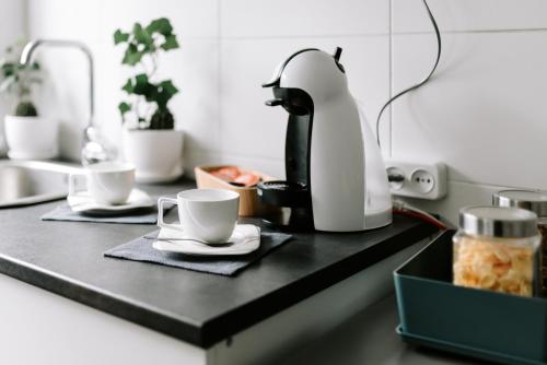 eine Kaffeemaschine und zwei Tassen auf der Theke in der Unterkunft Lake Aluksne studio apartment in Alūksne