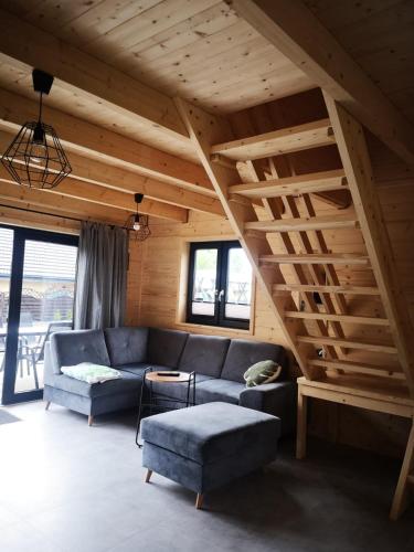 a living room with a blue couch and a wooden ceiling at Domki Dobrogoszcz in Dobrogoszcz