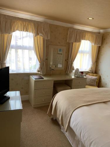 a bedroom with a bed and a desk and window at The Old Coach House in Blackpool