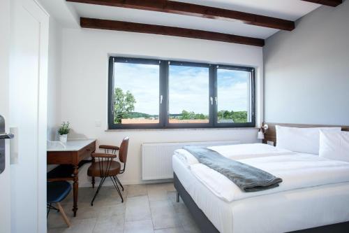 Schlafzimmer mit einem Bett, einem Schreibtisch und einem Fenster in der Unterkunft JUNIPRO Apartments Bostalsee in Bosen-Eckelhausen