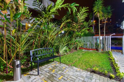 a black bench sitting in a garden with plants at The Morgana Poblado Suites Hotel in Medellín