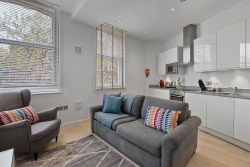 a living room with a couch and a kitchen at West Street by Aeria Apartments in London