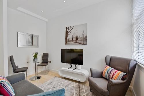 a living room with a flat screen tv and chairs at West Street by Aeria Apartments in London