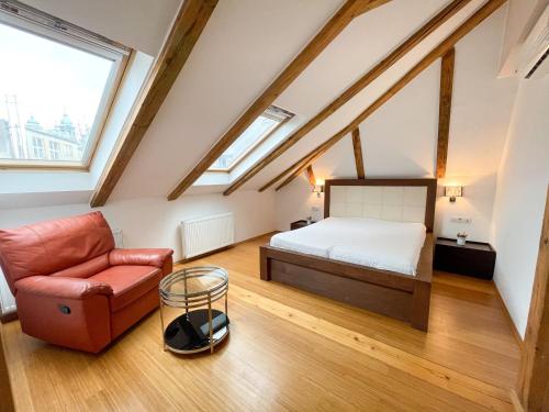 a attic bedroom with a bed and a chair at Žatecká 4 - Terrace Residence in the Old Town in Prague