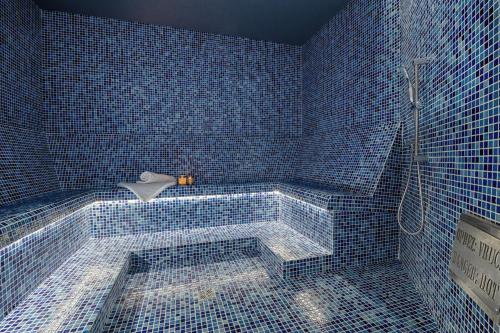 a blue tiled bathroom with a tub with a shower at Marea Hotel & Spa in Neum