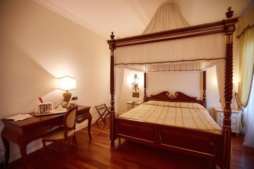 a bedroom with a canopy bed with a desk and a desk at Hotel Villa Il Patriarca in Chiusi