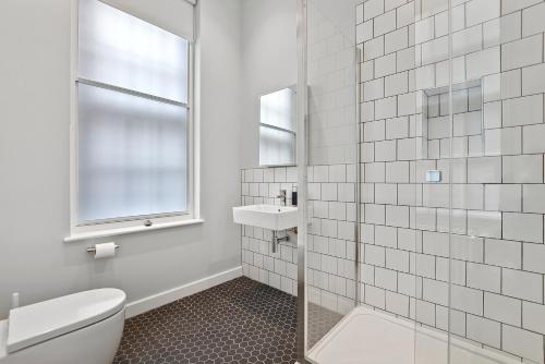a white bathroom with a toilet and a sink at GERRARD PLACE by Q Apartments in London