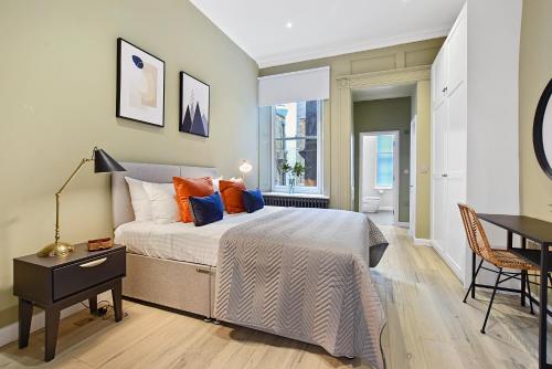 a bedroom with a bed and a table and a desk at GERRARD PLACE by Q Apartments in London