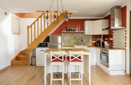 une cuisine avec des armoires blanches et un comptoir avec des tabourets dans l'établissement Villa Gecko, à Saint-Rémy-de-Provence