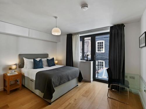 a bedroom with a bed and a large window at Cambric by Aeria Apartments in London