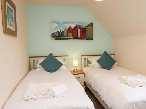 two twin beds in a bedroom with a painting on the wall at Sleeper Cottage in Filey