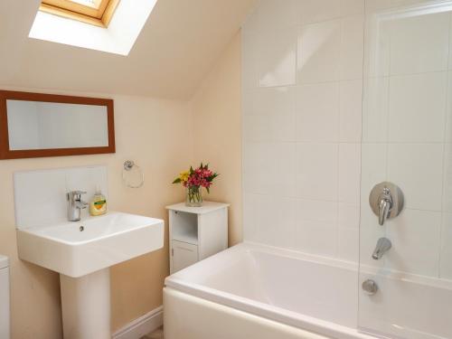 a white bathroom with a sink and a shower at Sleeper Cottage in Filey