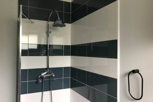 een badkamer met een douche met zwarte en witte tegels bij Maison avec jardin dans village in Réaup