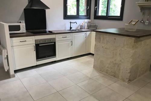 a kitchen with white cabinets and a counter top at Maison avec jardin dans village in Réaup