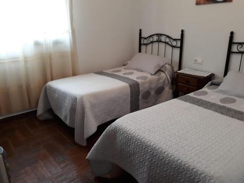 1 dormitorio con 2 camas y suelo de madera en Trujilllo Holiday Home, en Conil de la Frontera