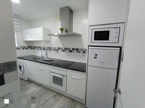 a white kitchen with a refrigerator and a microwave at Los Nidos Sea Pretty&Beach- La Carihuela in Torremolinos