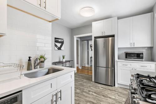 a kitchen with white cabinets and a stainless steel refrigerator at Chic 1BR Apt Close to Everything - Marshfield E3 in Chicago
