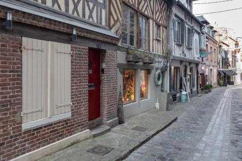 una strada vuota con un edificio in mattoni con una porta rossa di La maison Confidentielle - plein centre historique - 2 chambres - 4 pers a Honfleur