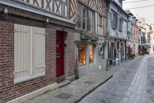 una calle vacía con un edificio de ladrillo con una puerta roja en La maison Confidentielle - plein centre historique - 2 chambres - 4 pers, en Honfleur