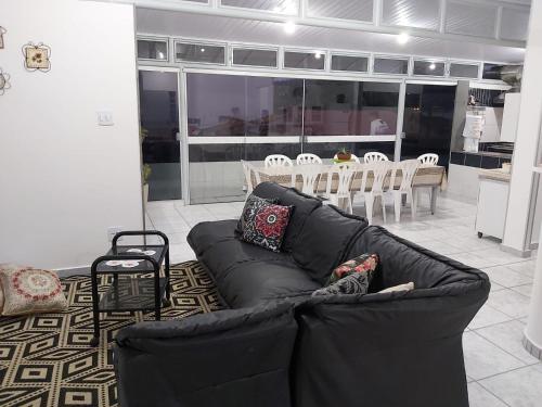 a living room with a black couch and a table and chairs at Apto para até 6 pessoas, 600 metros da Basílica in Aparecida