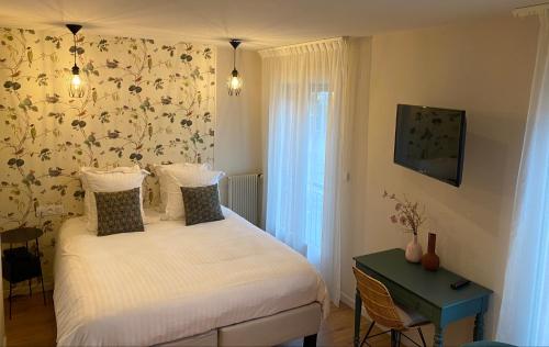 a bedroom with a bed and a table with a window at Hôtel Les Bains in Saint-Valery-en-Caux