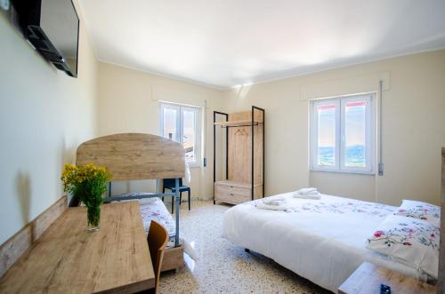 Colobraro的住宿－Girastrittue Colobraro，一间卧室配有一张床、一张桌子和两个窗户